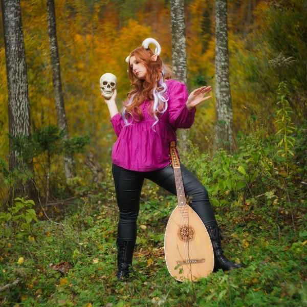 An Austin D&D Tiefling Bard poses with her instrument and a skull.